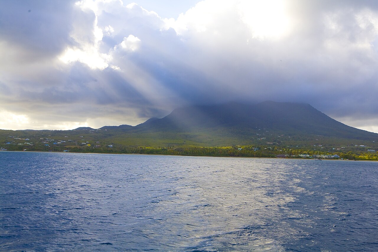 Sunlight breaking through cloud over Nevis Peak and the island's west coast shoreline, Nevis