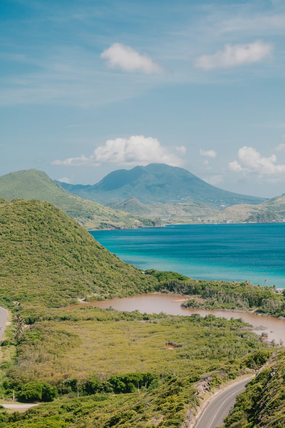 Green hills meet blue ocean under a cloudy sky in Saint Kitts and Nevis